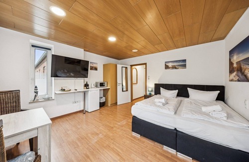 Wilhelmshaven Hotel | Cozy double room, seating area, flat-screen TV, and modern bathroom with shower. Ideal for couples and short stays – enjoy a relaxed atmosphere with warm wood accents and coastal charm.