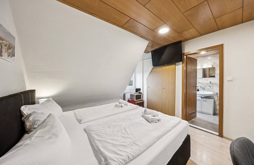 Wilhelmshaven Hotel | Cozy double room, flat-screen TV, and modern bathroom with shower. Ideal for couples and short stays – enjoy a relaxed atmosphere with warm wood accents and coastal charm.