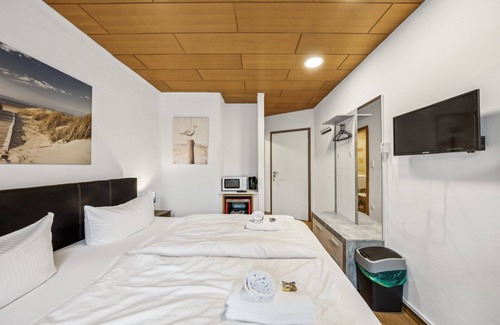 Wilhelmshaven Hotel | Cozy double room, flat-screen TV, and modern bathroom with shower. Ideal for couples and short stays – enjoy a relaxed atmosphere with warm wood accents and coastal charm.