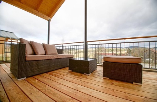 Bohmzwiesel Apartment | Ferienchalet mit überdachter Veranda mit Lounge Möbel und Schwebeliege.