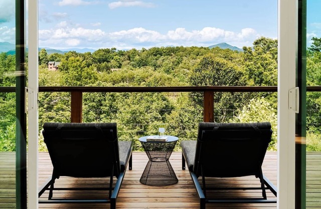 EcoModMtn is a 3BR/3.5BA luxury retreat with panoramic fall views, floor-to-ceiling windows, a gas fireplace, private hot tub, firepit, and designer kitchen. Perfect for families, couples, or friends seeking cozy mountain elegance this autumn.