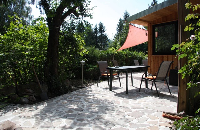 Modernly furnished bungalow with fireplace, surrounded by greenery.