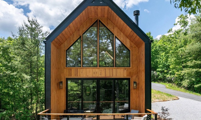 Young Harris Cabin | Romance meets design at Viking Hut, a Scandinavian 1BR retreat in the North Georgia mountains. Floor-to-ceiling windows frame fiery fall leaves, a skylight invites stargazing from your king bed, and a fenced yard makes it perfect for pups.