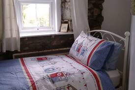 Helston House | Twin bed room with exposed stone wall